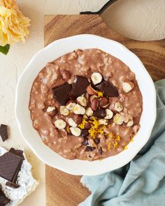 a bowl of oatmeal with nuts and chocolate in it on a table