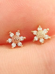 a pair of small diamond stud earrings on someone's finger