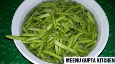 a bowl filled with green beans on top of a table