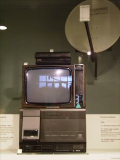 an old tv sitting on top of a shelf next to a satellite dish and antenna