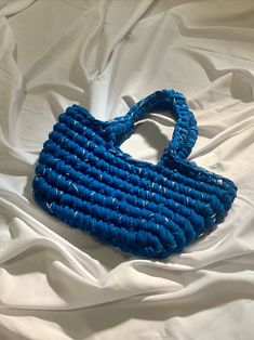 a blue purse sitting on top of a white sheet