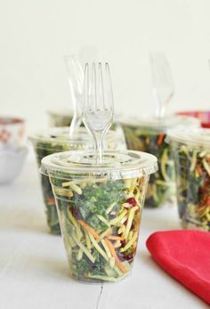 several plastic cups filled with salad and forks