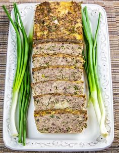 meatloaf with green onions on a white platter, ready to be eaten