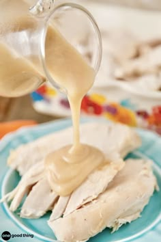 a person pouring sauce onto some food on a plate