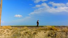 a man standing on top of a train track in the middle of an open field