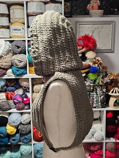 a mannequin wearing a crochet hat in front of a display of yarns