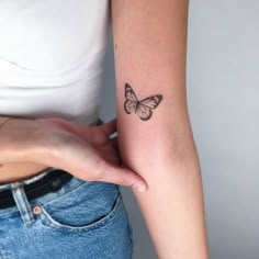 a woman's arm with a small butterfly tattoo on the back of her left arm