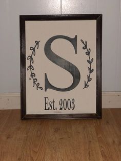 a framed sign with the letter s in black and white on a wooden floor next to a wall