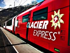 a red train with the word glacier express on it's side next to a platform