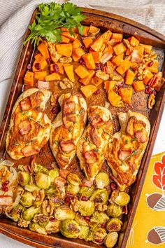 a wooden tray filled with meat and veggies on top of a white table cloth