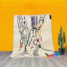 the rug is next to a cactus in front of a yellow wall