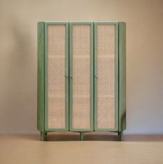 a green cabinet with woven panels on the front and sides, against a beige wall