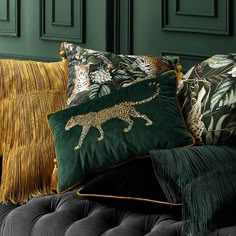 pillows on a couch with green wall in the background and gold fringe trim around them