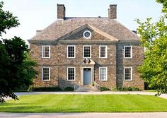 a large brick house with white trim and windows on the top floor is surrounded by green grass