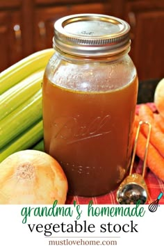 a jar filled with liquid sitting next to some carrots and celery on a table