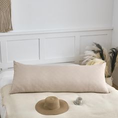 a bed with a hat on top of it next to a pillow and a feather