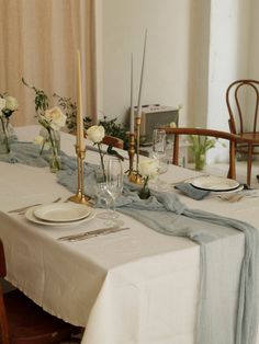 the table is set with white roses and place settings for two people to sit at