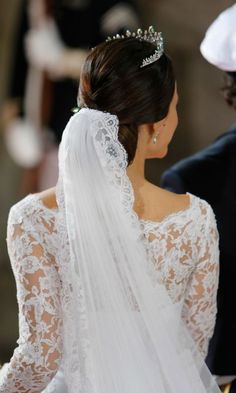 the back of a bride's dress with a veil and tiara on her head