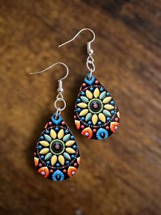 a pair of colorful earrings sitting on top of a wooden table