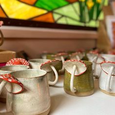 several coffee mugs with bows on them sitting on a table in front of a stained glass window