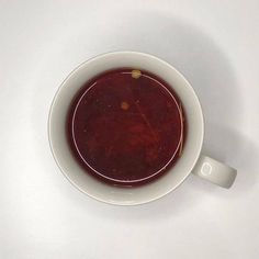 a white bowl filled with soup on top of a table next to a cup of coffee