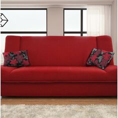 a red couch sitting in front of a window