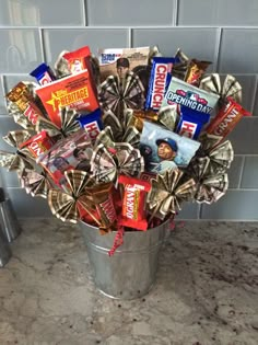 a metal bucket filled with candy and candies on top of a counter next to a tile wall