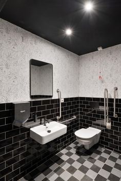 a black and white tiled bathroom with two urinals on the wall, one for the sink and the other for the toilet