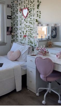 a bedroom with two beds and a desk in front of a window filled with plants