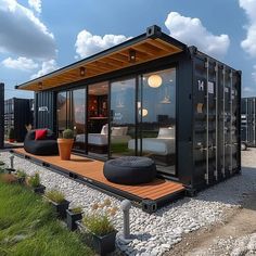 a black shipping container sitting on top of a lush green field next to a building