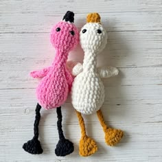 two crocheted stuffed animals sitting next to each other on a white wooden surface