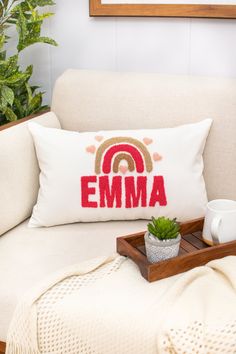 a white couch with a wooden tray holding a potted plant and a personalized pillow