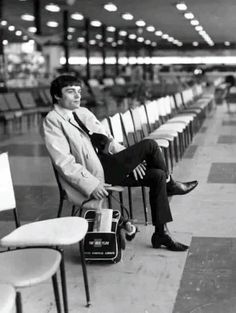 a man sitting on top of a chair next to a row of chairs in an airport