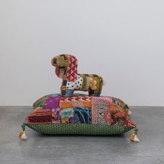 a colorful patchwork pillow with a dog figurine on top