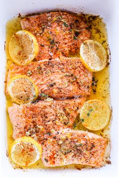 salmon with lemons and herbs in a white casserole dish