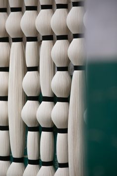 several white bowling pins are lined up against a green wall with black stripes on them