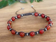 a red beaded bracelet sitting on top of a wooden table