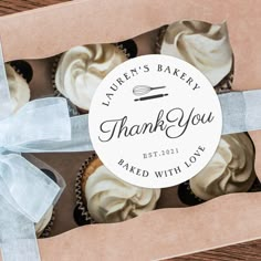 a box filled with cupcakes sitting on top of a wooden table next to a blue ribbon