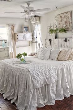 a white bed sitting in a bedroom on top of a hard wood floor next to a window