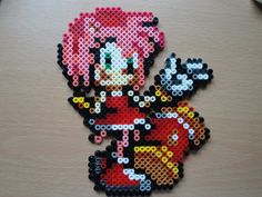 a piece of art made out of perler beads on a table next to a computer mouse