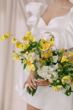 a woman holding a bouquet of yellow and white flowers