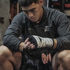 a man sitting on the ground with his hand wrapped around his wrist and wearing black gloves