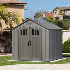 a gray shed sitting in the middle of a yard