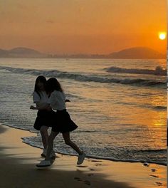 two girls walking on the beach at sunset