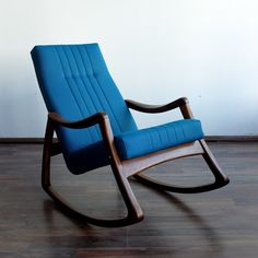 a blue rocking chair sitting on top of a hard wood floor next to a white wall