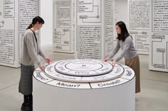 two women standing in front of a white circular display