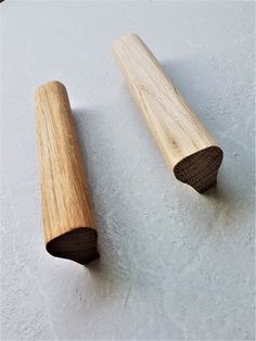 two pieces of wood sitting next to each other on a white surface with one piece cut in half