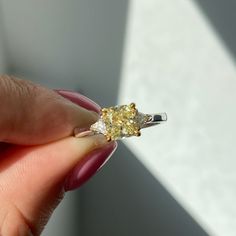 a woman's hand holding a yellow and white diamond ring