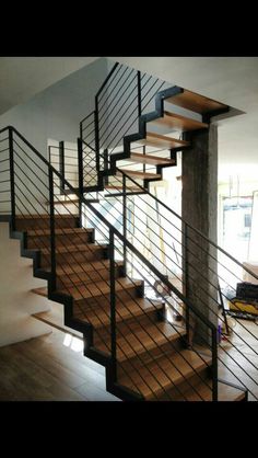 a stair case with metal railing and wood handrails in a house under construction