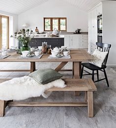 a dining room table with two benches in front of it and an open kitchen area